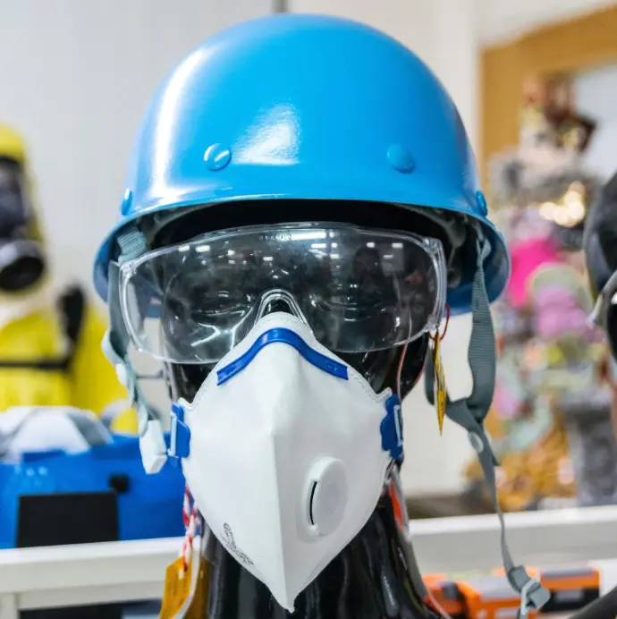 Mannequin wearing a blue hard hat and an N95 respirator mask